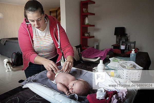 Reportage über eine unabhängige Hebamme bei Hausbesuchen nach der Geburt. Die Hebamme reinigt die Nabelschnur.