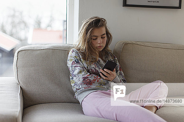 Teenager-Mädchen auf Sofa mit Handy