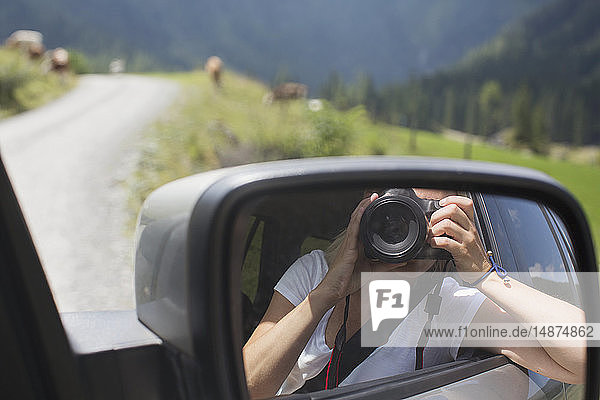Woman photographing herself in car mirror
