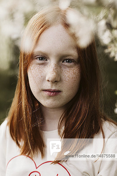 Rothaarige Teenagerin posiert im Obstgarten