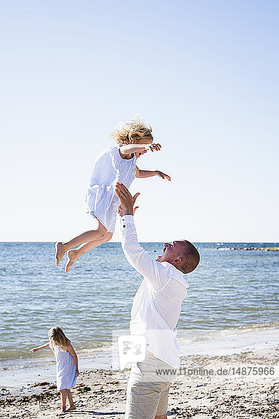 Vater spielt mit Tochter am Strand