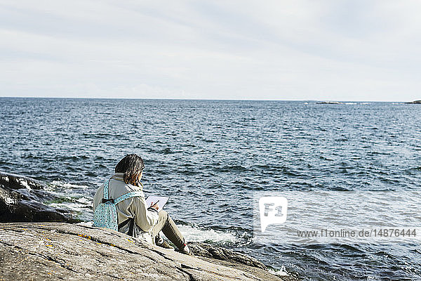 Jugendliches Mädchen schreibt Brief am Meer