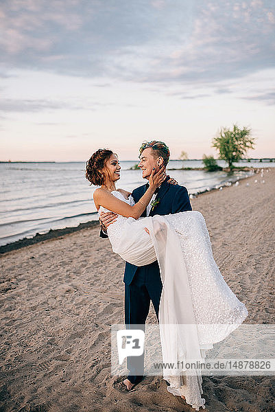 Romantic groom carrying bride on lakeside  Lake Ontario  Toronto  Canada