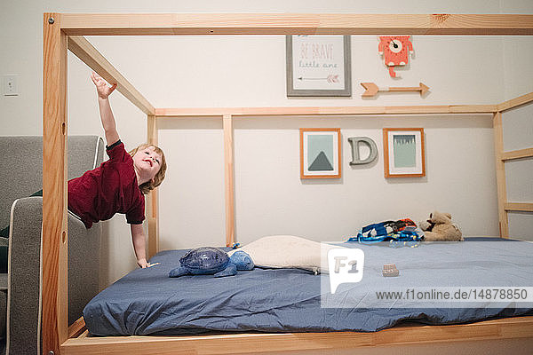 Boy climbing four poster bed