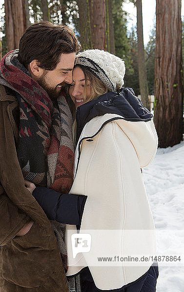 Junge Frau und Freund umarmen sich im Winterwald  Twain Harte  Kalifornien  USA