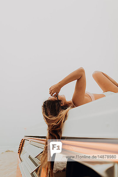 Junge Frau im Bikini auf einem Wohnmobil am Strand liegend  Jalama  Kalifornien  USA