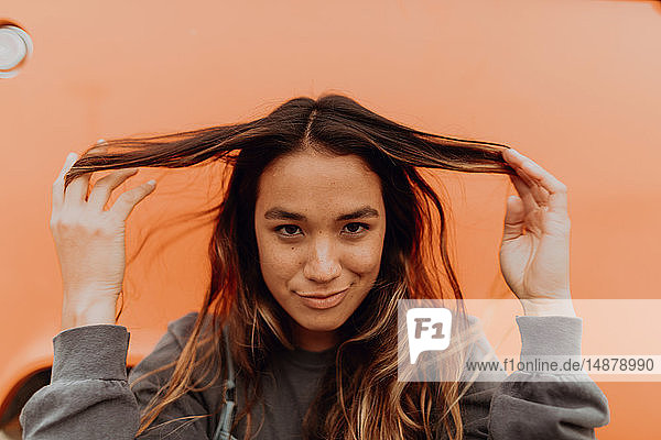 Junge Frau vor orangefarbenem Wohnmobil am Strand  Porträt  Jalama  Kalifornien  USA