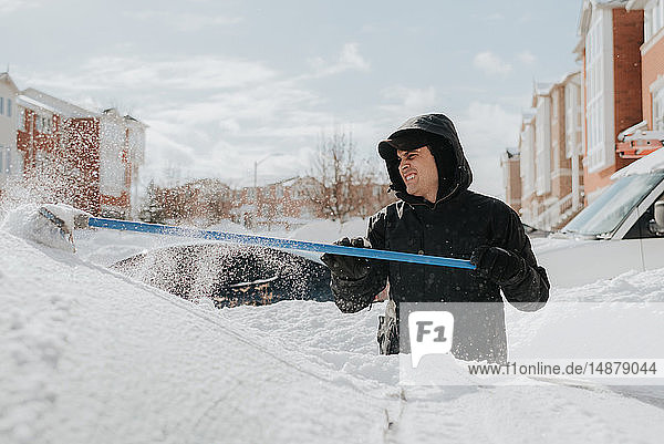 Mann räumt schneebedecktes Fahrzeug mit Besen  Toronto  Kanada