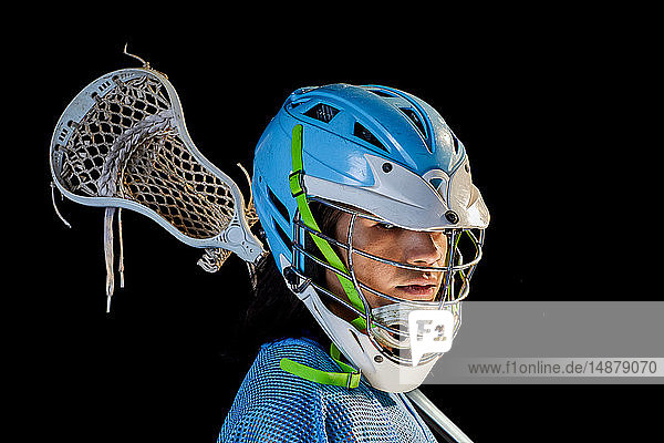 Junger männlicher Lacrosse-Spieler mit Lacrosse-Schläger  Portrait vor schwarzem Hintergrund