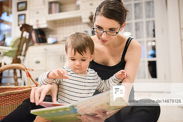 Baby boy and mother reading on floor