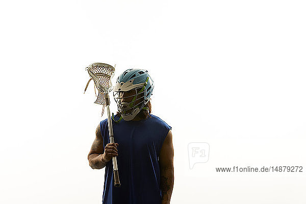 Junger männlicher Lacrosse-Spieler mit Lacrosse-Schläger auf der Schulter  Porträt vor weissem Hintergrund
