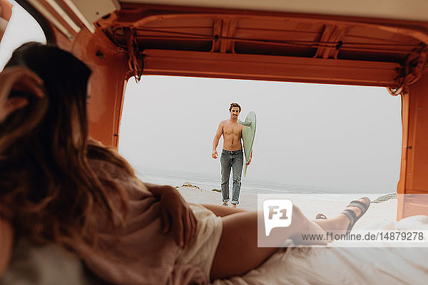 Junge Frau  die auf dem Rücksitz eines Wohnmobils liegt und am Strand auf ihren Surfer-Freund wartet  Jalama  Ventura  Kalifornien  USA