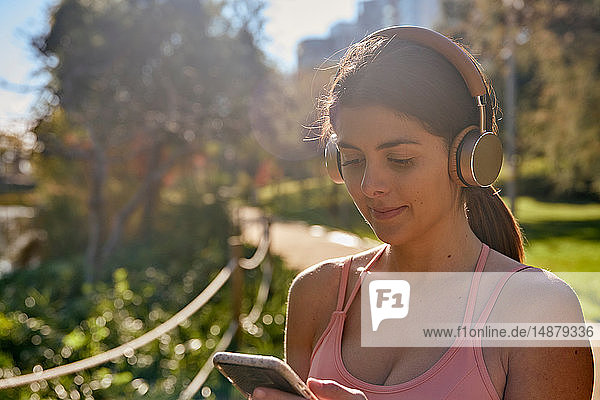 Frau  die im Stadtpark mit Kopfhörern Musik hört