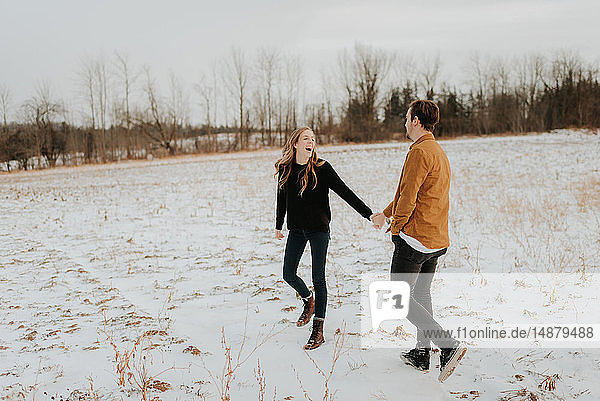Glückliches Paar geniesst Spaziergang im verschneiten Feld