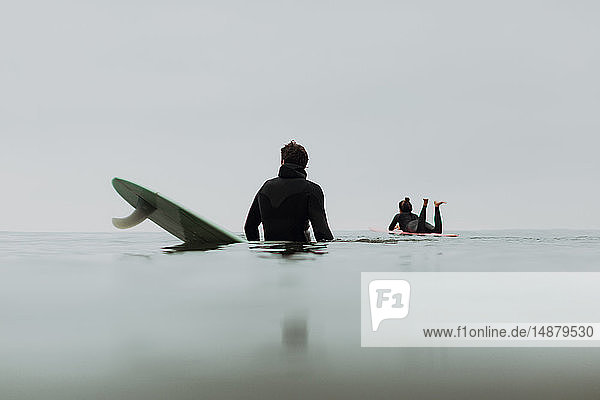 Junges Surferpaar auf Surfbrettern bei ruhiger nebliger See  Ventura  Kalifornien  USA