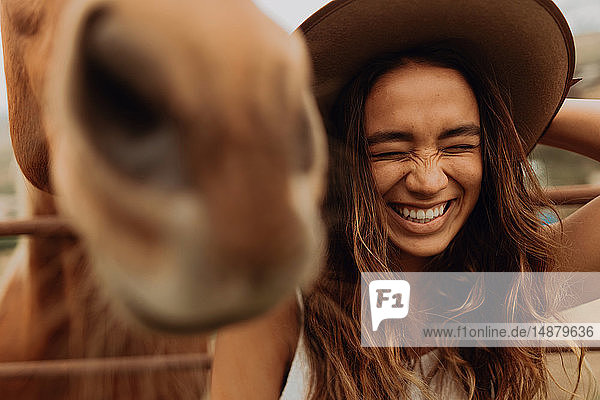 Young woman in felt hat laughing next to horse  Jalama  California  USA