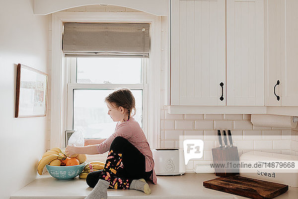 Mädchen ordnet Früchte im Korb auf der Küchenarbeitsplatte an