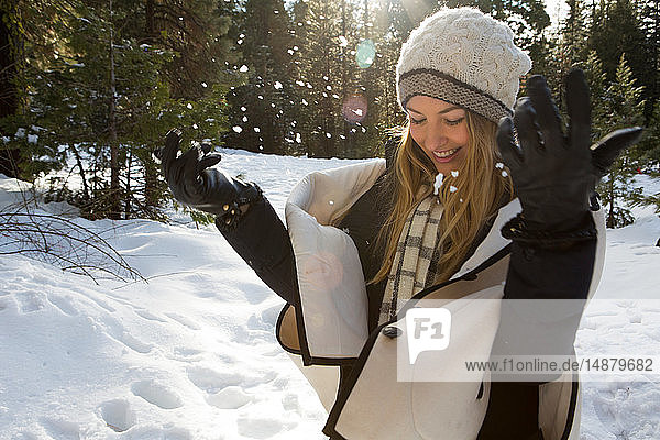Junge Frau spielt mit Schnee im Winterwald  Twain Harte  Kalifornien  USA