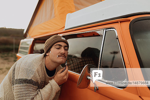 Junger Mann rasiert sich am Außenspiegel eines Wohnmobils  Jalama  Kalifornien  USA