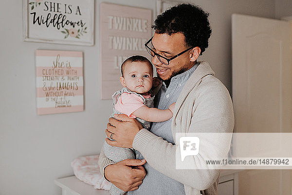 Father with baby daughter in baby's room