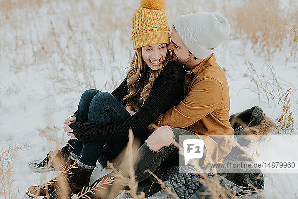 Happy couple sitting on snowy field