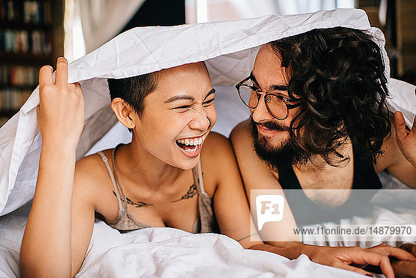 Happy couple under covers in bed