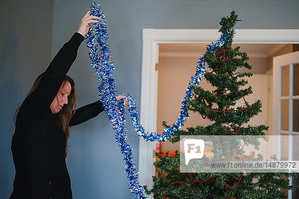 Frau schmückt Weihnachtsbaum