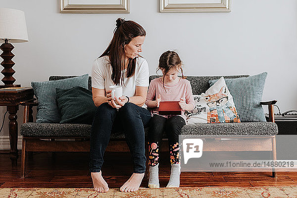 Mother watching daughter play on couch