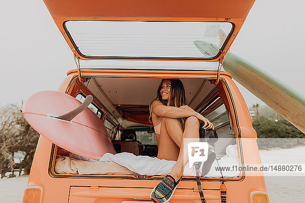 Junge Frau hält Sofortbildkamera auf dem Rücksitz eines Wohnmobils am Strand  Jalama  Kalifornien  USA
