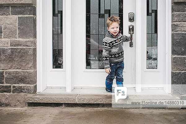 Boy closing door to leave house