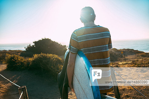 Junger Mann mit Surfbrett am Strand  Morro Bay  Kalifornien  Vereinigte Staaten