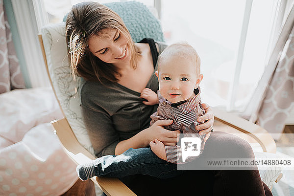 Baby boy sitting on mother's lap in living room  portrait