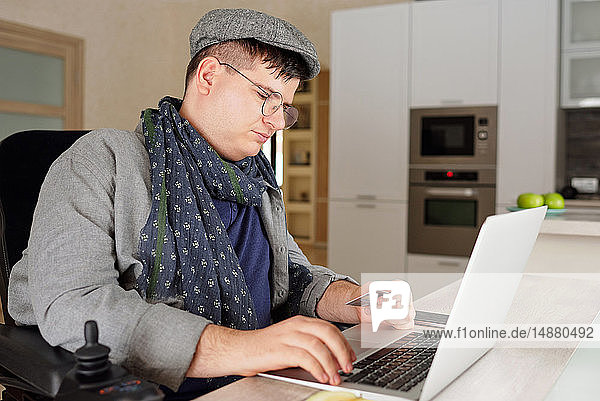 Körperlich behinderter Mann macht Online-Einkauf am Laptop zu Hause