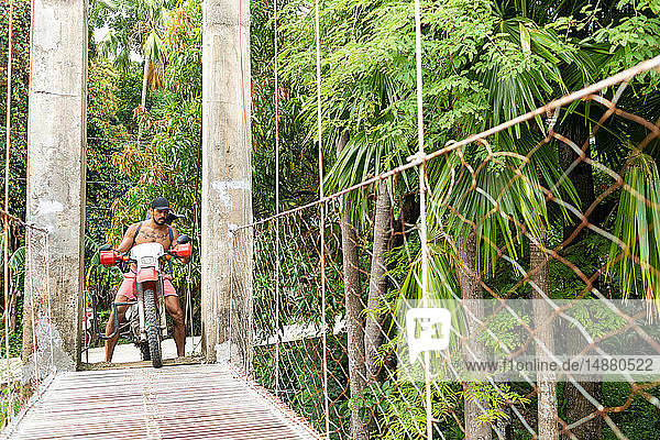 Motorradfahrer mit Surfbrett auf Seilbrücke  Pagudpud  Ilocos Norte  Philippinen