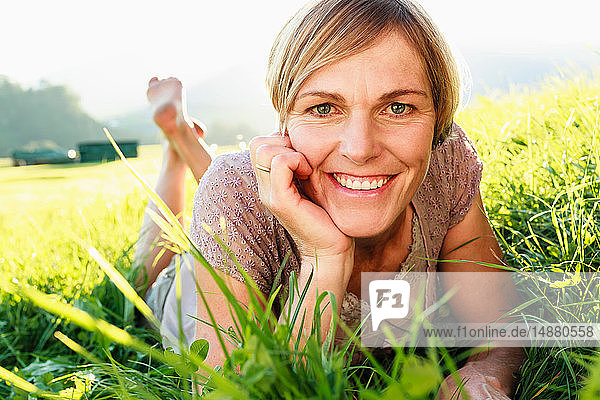 Frau liegt im Gras auf dem Land