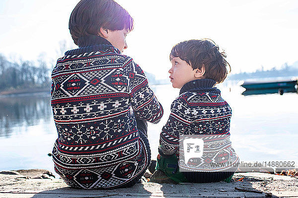 Junge und kleiner Bruder im passenden Pullover im Gespräch am Pier Comer See Lecco Lombardei Italien