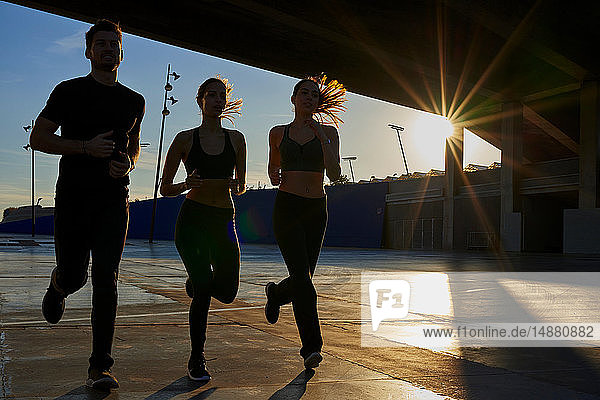 Freunde joggen bei Sonnenuntergang im Sportstadion