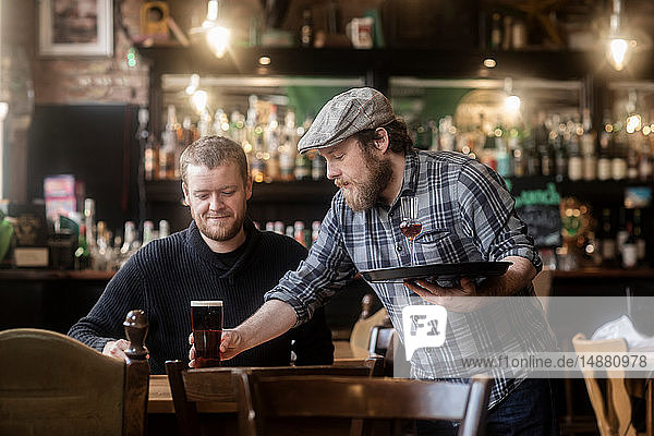 Barkeeper serviert Bier an Kunden in traditionellem irischen Wirtshaus