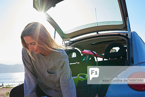 Young woman standing behind open car boot