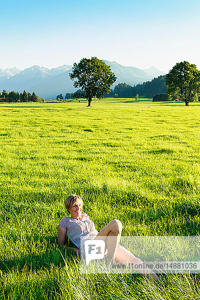 Frau liegt im Gras auf dem Land  Sonthofen  Bayern  Deutschland