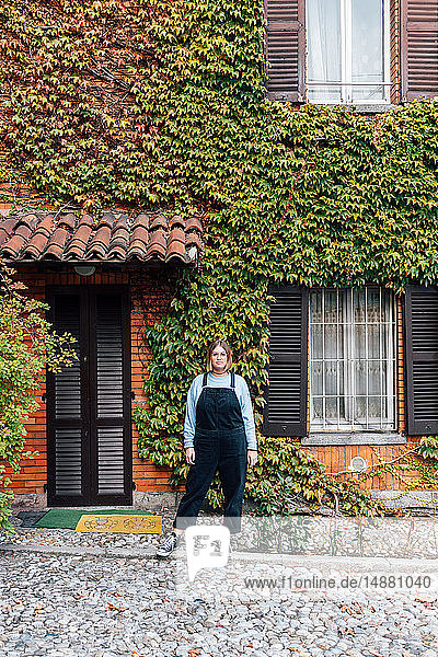 Woman outside house with facade covered in ivy  Rezzago  Lombardy  Italy