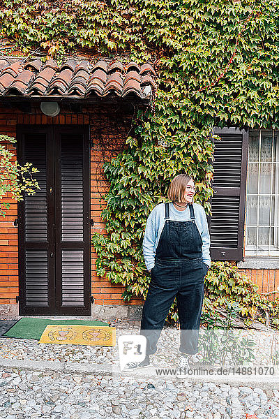 Woman outside house with facade covered in ivy  Rezzago  Lombardy  Italy