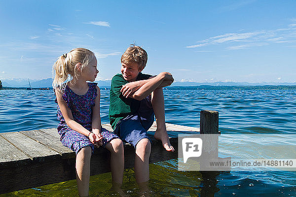 Geschwister kühlen Füße im Wasser  Starnberger See  Bayern  Deutschland