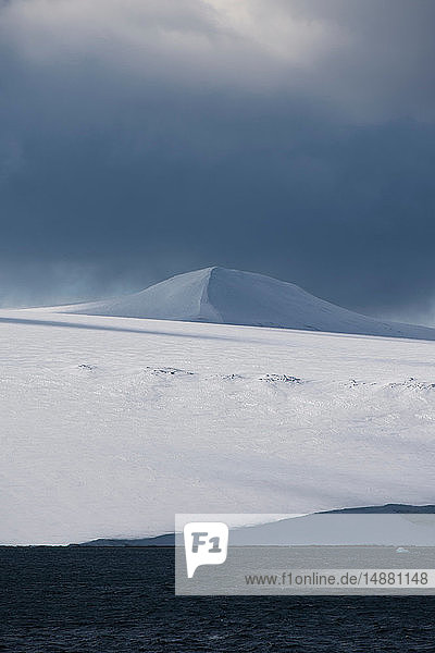 Schneebedeckte Küstenlandschaft mit Sturmwolken  Hinlopen-Straße  zwischen Nordaustlandet und Spitzbergen  Svalbard  Norwegen