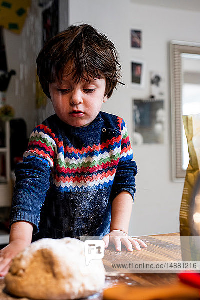 Kleinkind knet Teig auf Küchenarbeitsplatte