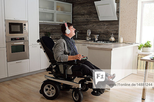 Körperbehinderter Mann  der zu Hause mit Kopfhörern Musik hört