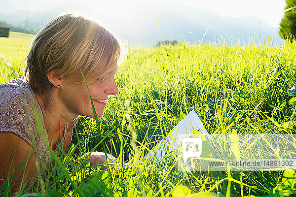 Frau liest Buch über Gras auf dem Land  Sonthofen  Bayern  Deutschland