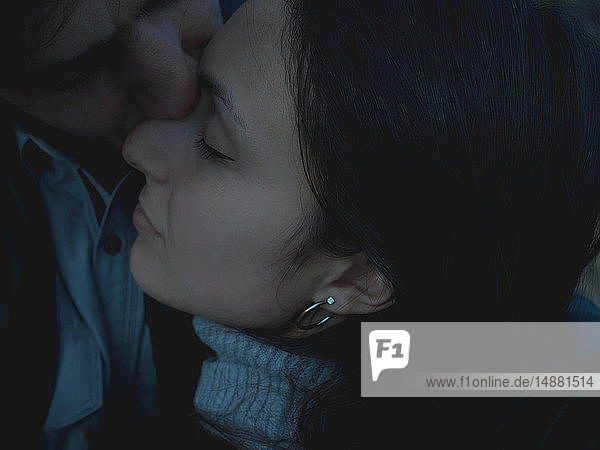 Mann küsst Frau mit geschlossenen Augen auf die Nase