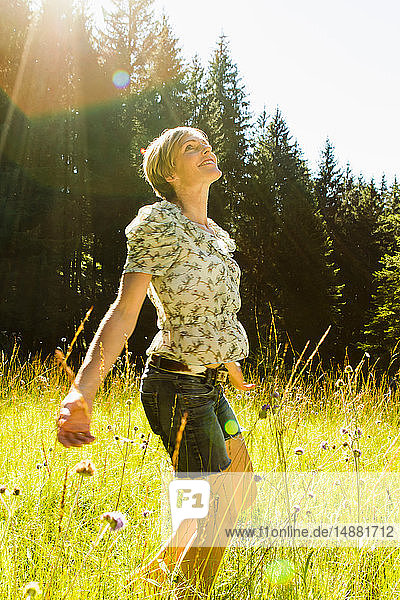 Frau tanzt zwischen wilden Blumen im Wald  Sonthofen  Bayern  Deutschland