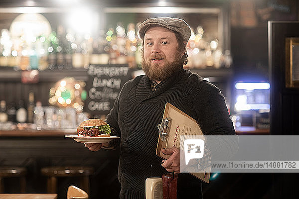 Man with plate of burger and menu in pub